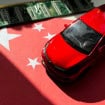 Miniatura de carro em cima de miniatura de bandeira da China; ambos estão ao lado de um chip