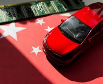 Miniatura de carro em cima de miniatura de bandeira da China; ambos estão ao lado de um chip
