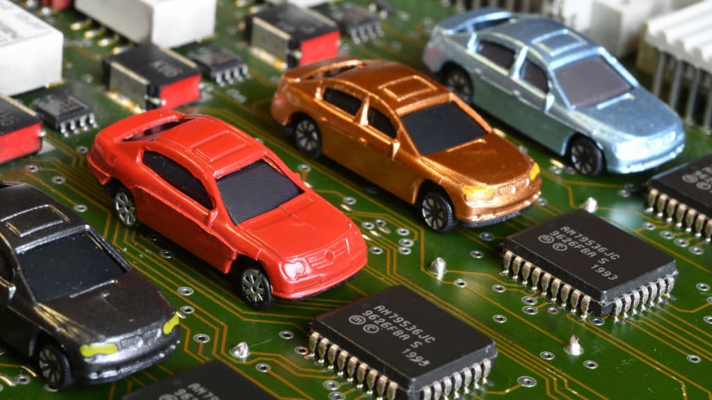 Miniaturas de carros colocadas ao lado de chips em placa de computador