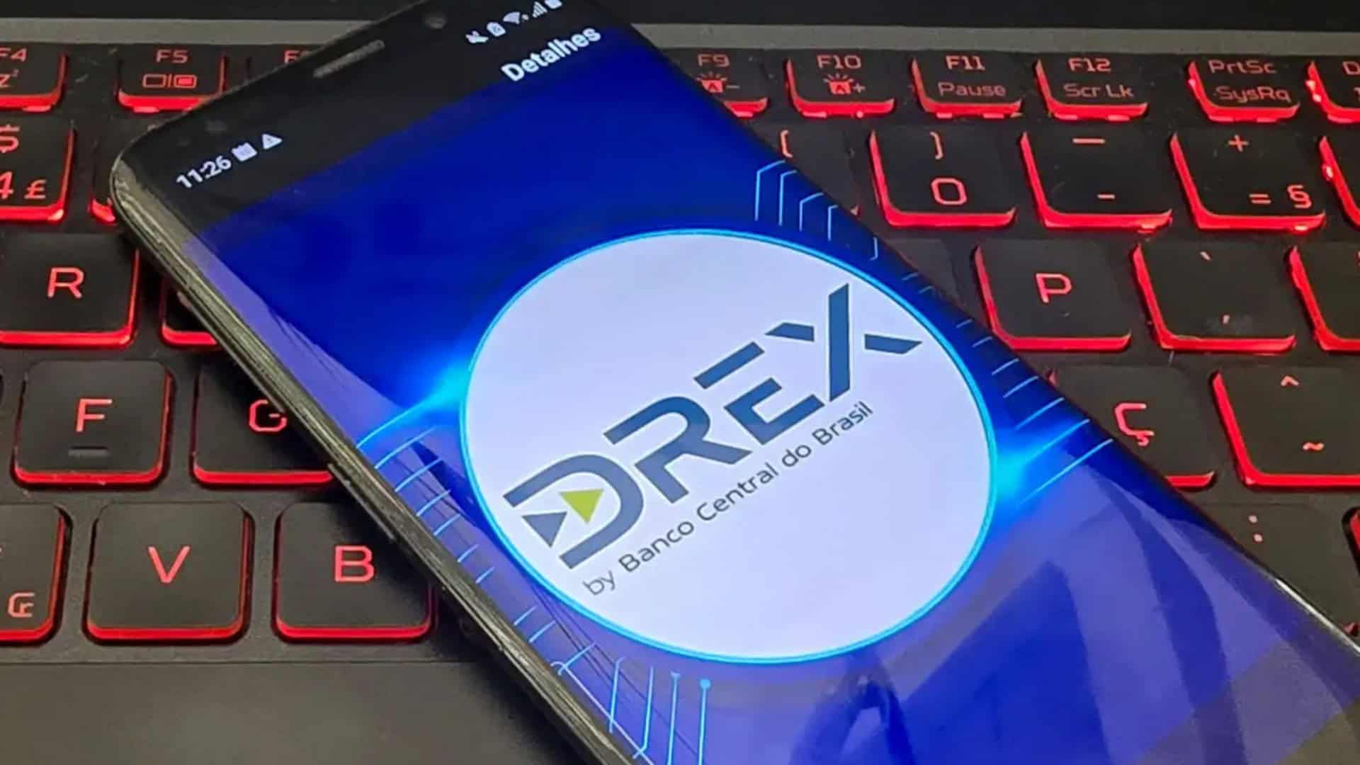 Celular com logomarca do Drex na tela colocado em cima de teclado de notebook