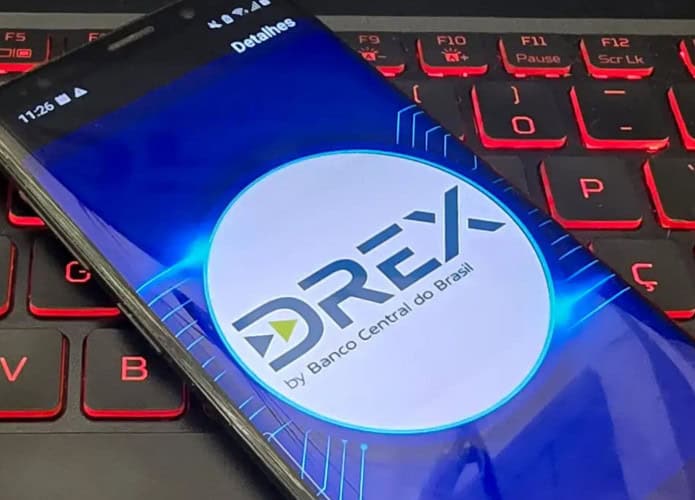 Celular com logomarca do Drex na tela colocado em cima de teclado de notebook