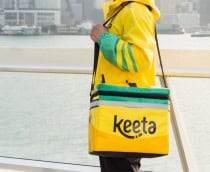 Homem em pé com uniforme e bolsa da Keeta