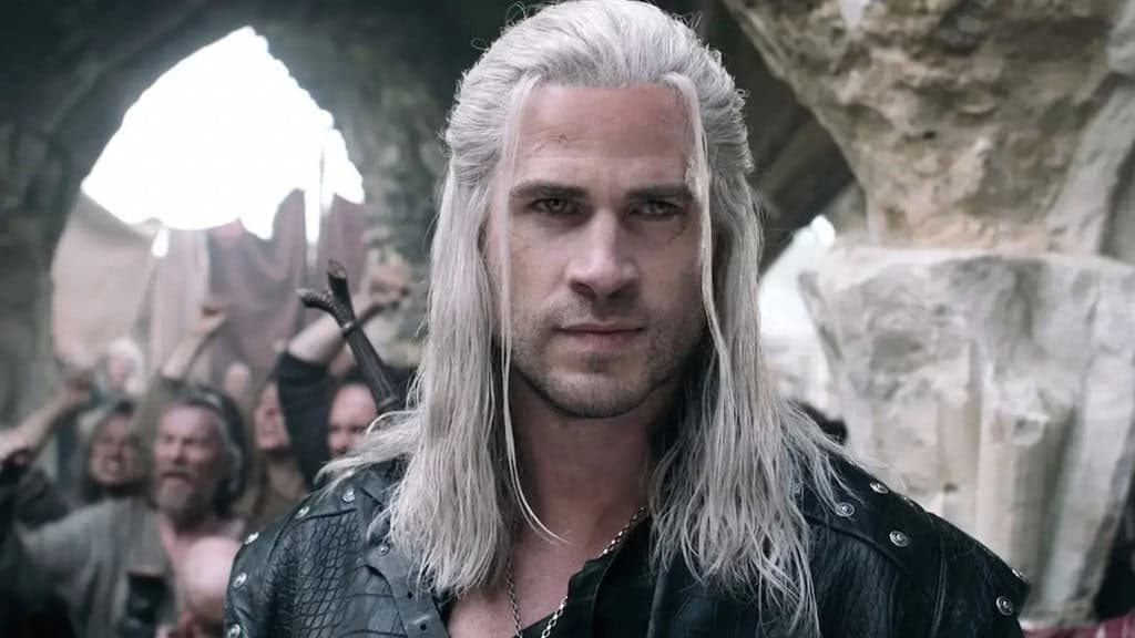 Liam Hemsworth caracterizado como Geralt de Rívia, com cabelos brancos e expressão séria, usando armadura de couro preta e espada nas costas, em cena da 4ª temporada de The Witcher