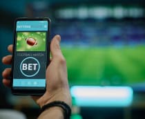 Ao fundo, borrado, uma partida de futebol passando em uma TV; à frente, a foto de uma bola de futebol americano e a palavra 