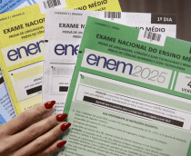 pessoa com unhas vermelhas segurando cadernos do Enem