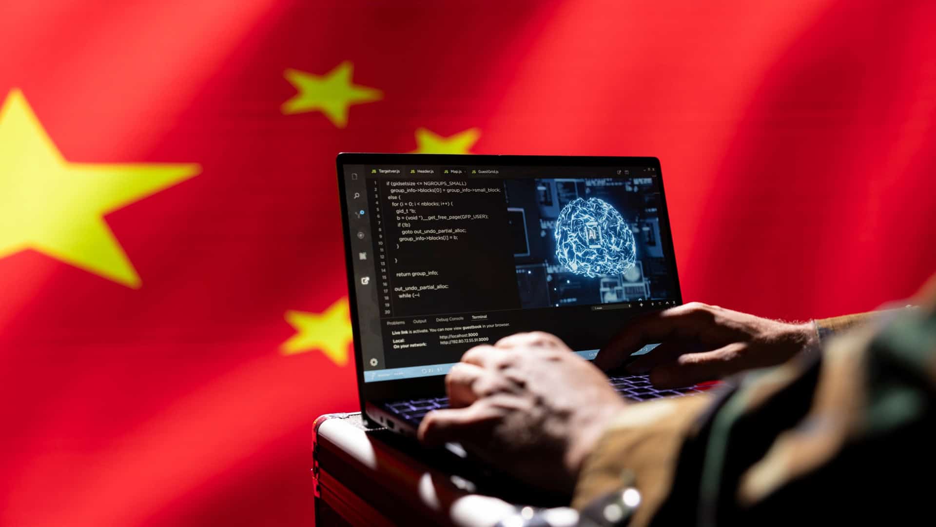 Ao fundo, bandeira da China; à frente, pessoa teclando em um notebook