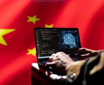 Ao fundo, bandeira da China; à frente, pessoa teclando em um notebook