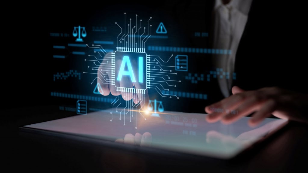 Pessoa tocando um tablet, do qual está sendo projetada uma imagem com os dizeres "AI"