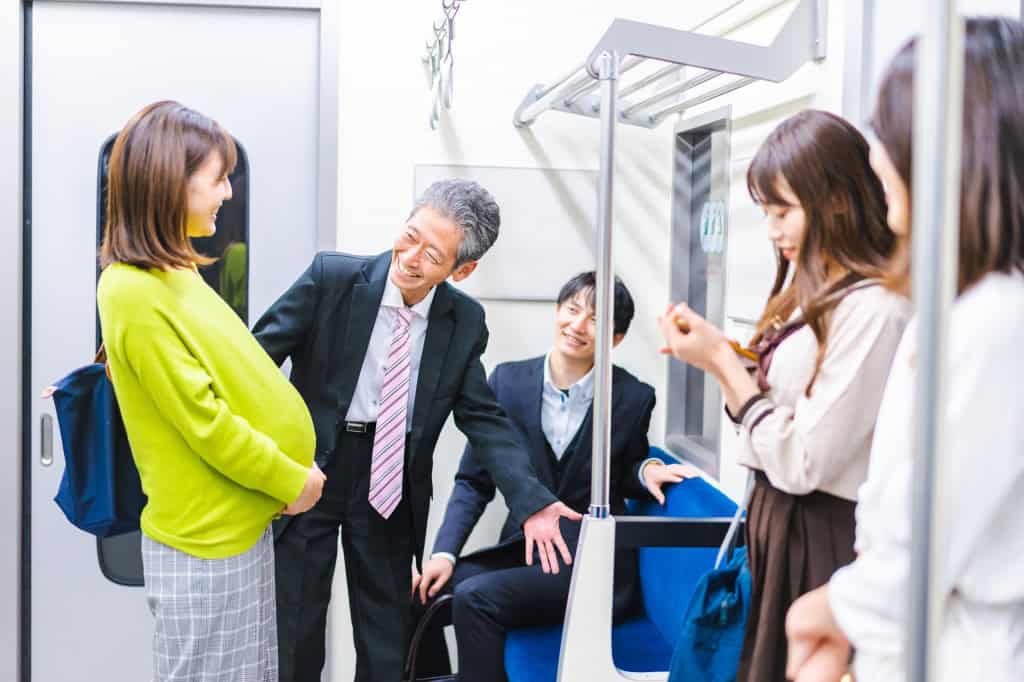 Homem cedendo lugar no metrô para uma mulher grávida