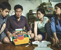 cena do filme Parasita, onde a família monta caixas de pizza em casa