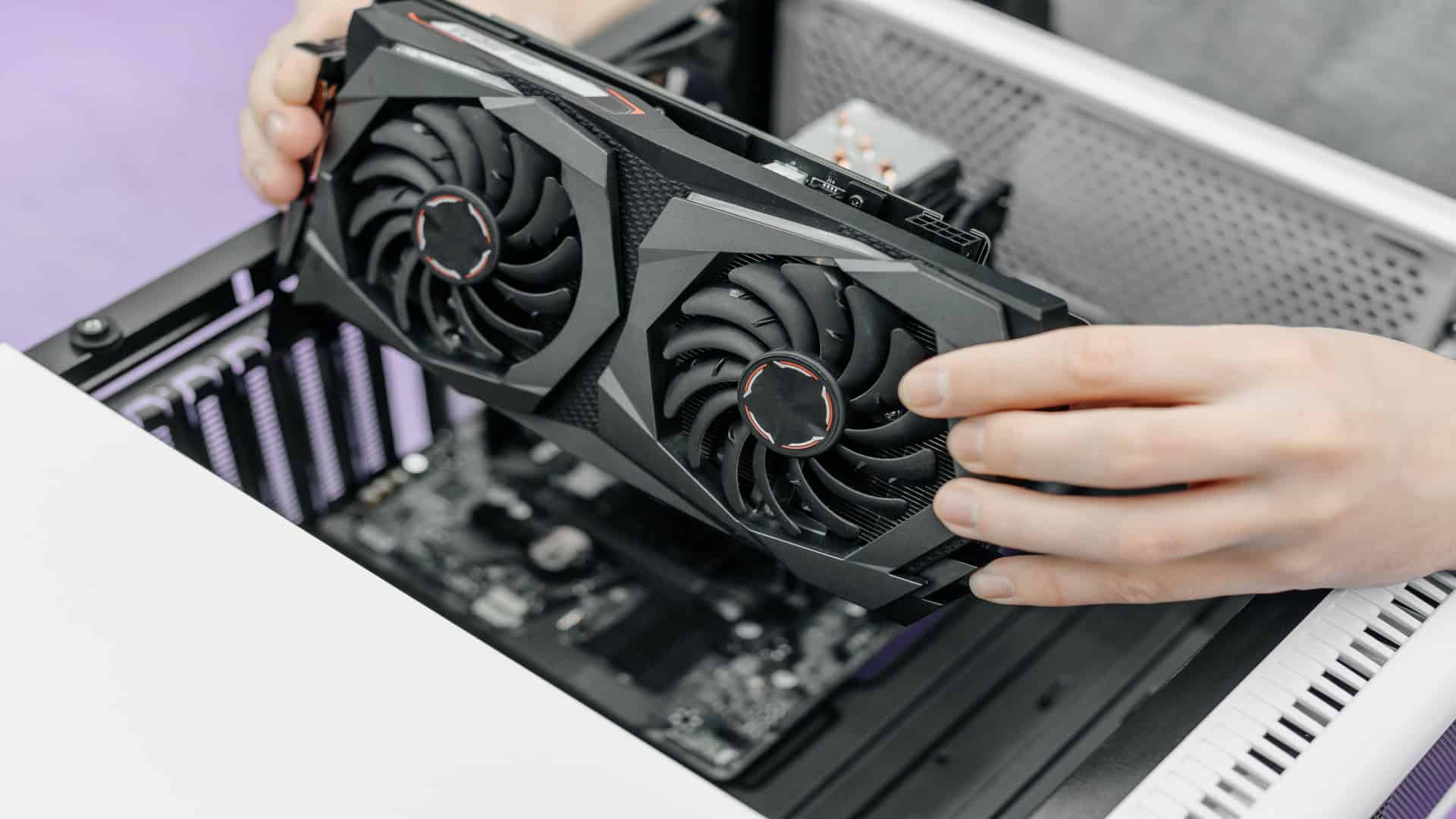 Pessoa instalando uma placa de vídeo em um desktop, com a placa-mãe visível, representando o processo de atualização de hardware do PC