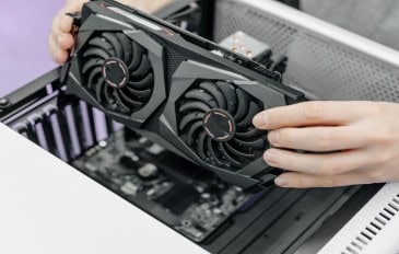 Pessoa instalando uma placa de vídeo em um desktop, com a placa-mãe visível, representando o processo de atualização de hardware do PC