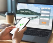 Pessoa segurando um celular em frente a um notebook