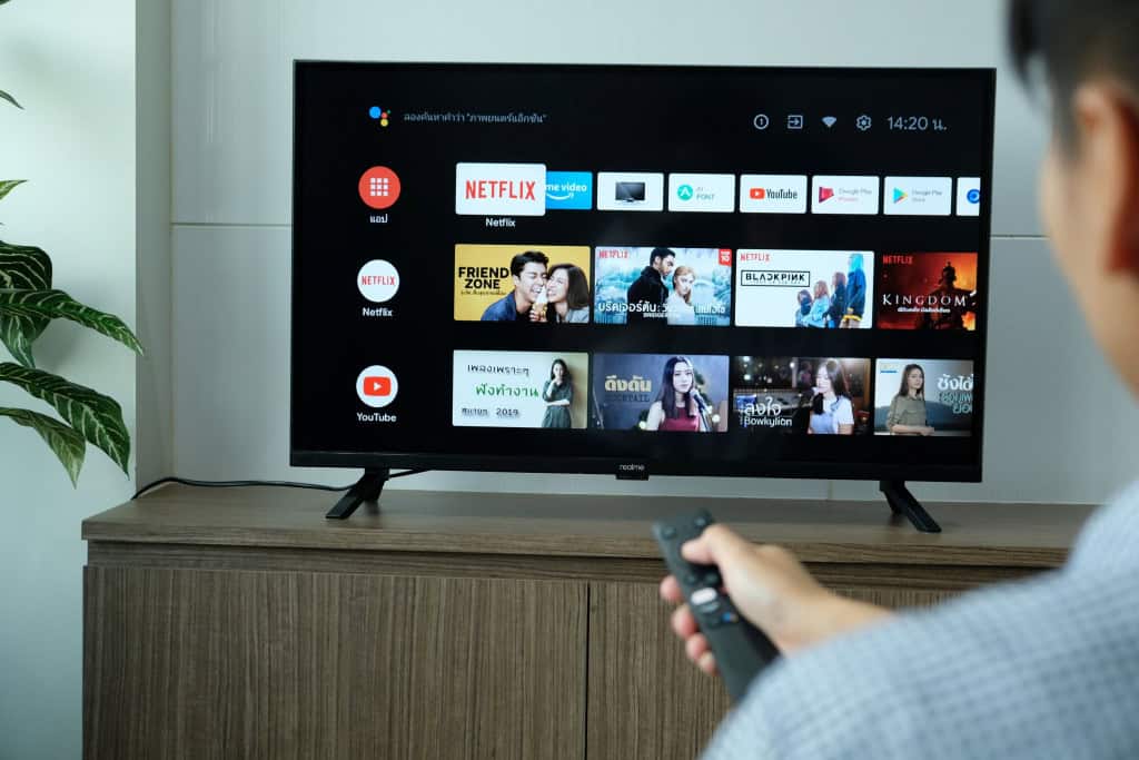 Pessoa usando controle remoto para acessar menu de configurações de Smart TV