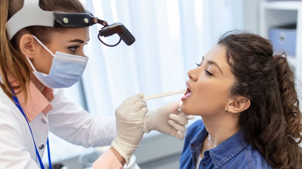 médica verificando a garganta de uma jovem.