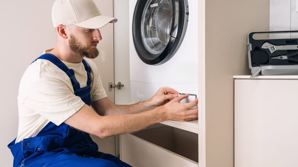 Técnico de assistência consertando máquina de lavar