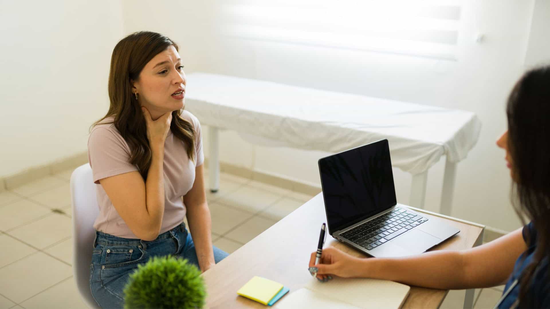 mulher com mão na garganta em consultório, descrevendo sintomas ao médico