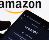 Pessoa segurando celular no qual aparece uma conversa no ChatGPT, da OpenAI; no fundo, uma tela exibe a logomarca da Amazon
