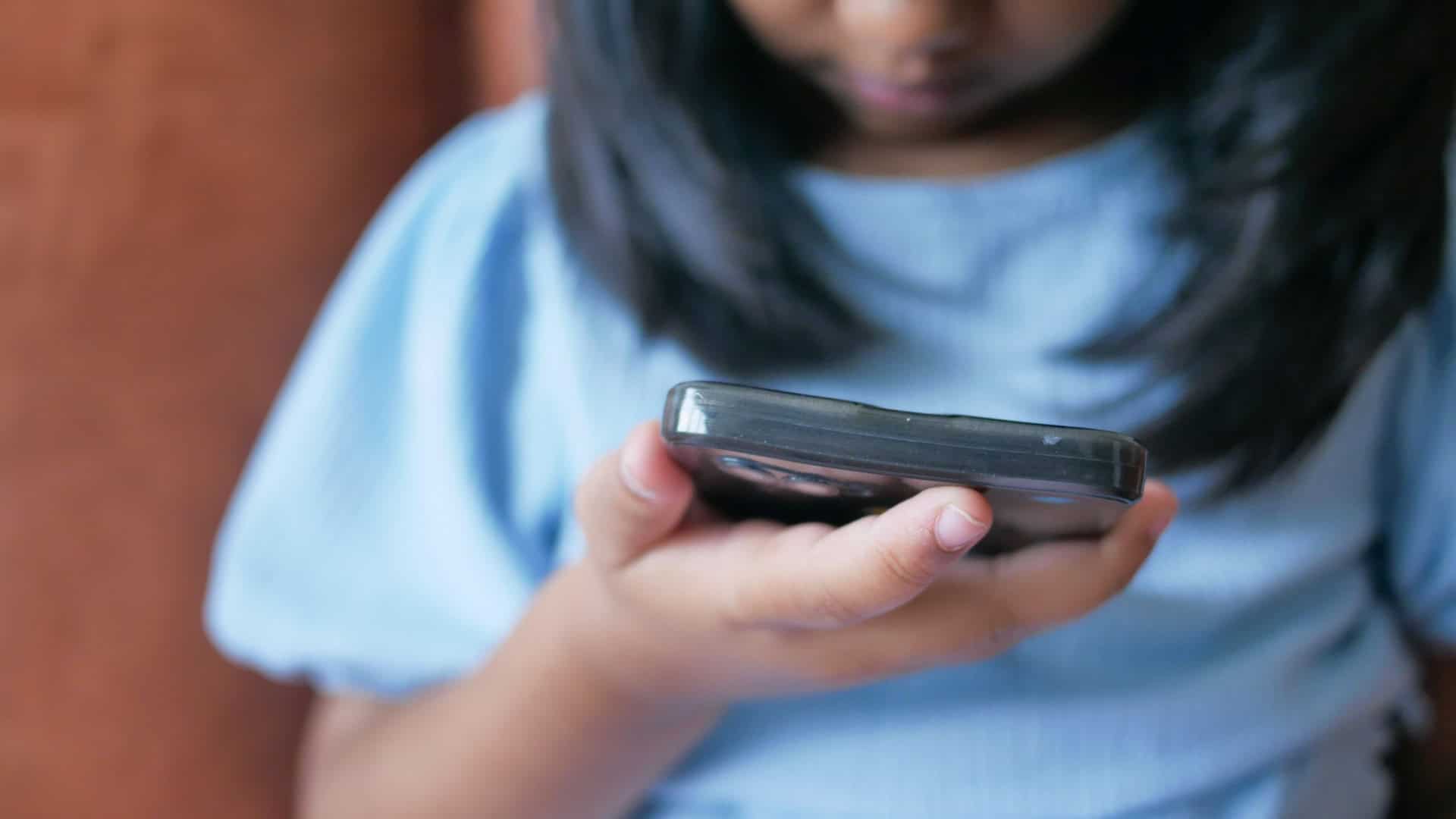 Foto bem de perto de menina usando celular