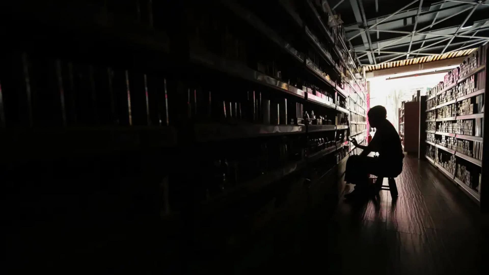 Silhueta de pessoa sentada em estabelecimento comercial durante período de falta de energia