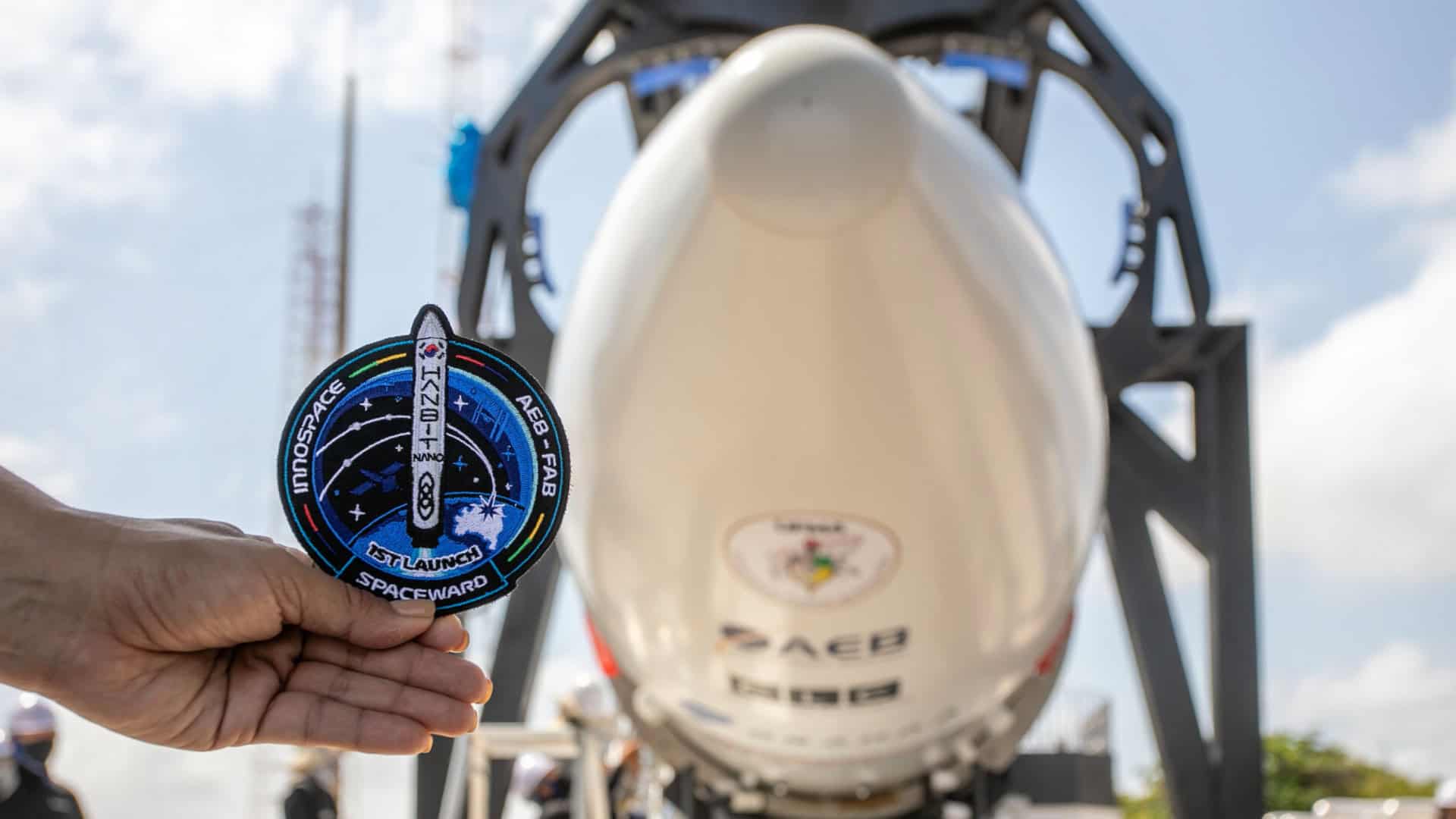 Pessoa segurando símbolo da Operação Spaceward na frente do foguete HANBIT-Nano da Innospace na Base de Alcântara