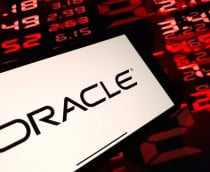 Pessoa segurando celular com logomarca da Oracle na tela na frente de tela mostrando números de ações financeiras vermelhos