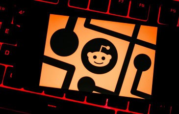 Ilustração com logomarca do Reddit em cima de teclado de notebook com teclas com retroiluminação vermelha acesa