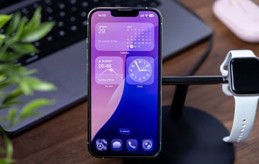 iPhone com iOS 26 instalado colocado num suporte ao lado de um Apple Watch