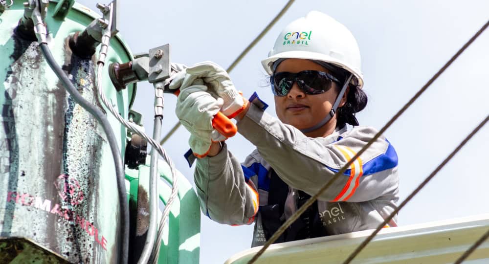 Mulher com ferramenta na mão consertando uma peça de um poste elétrico