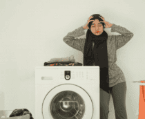 mulher preocupada ao lado de máquina de lavar