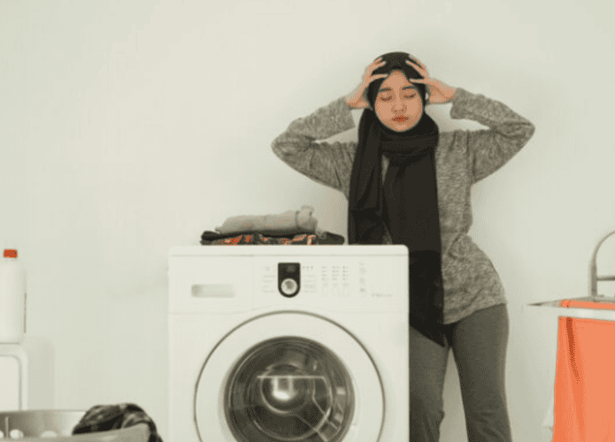 mulher preocupada ao lado de máquina de lavar