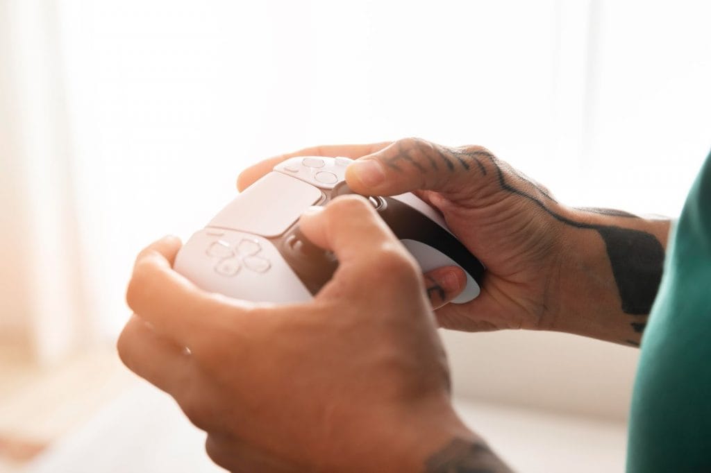 Jogador jogando videogame com controle DualSense do PlayStation