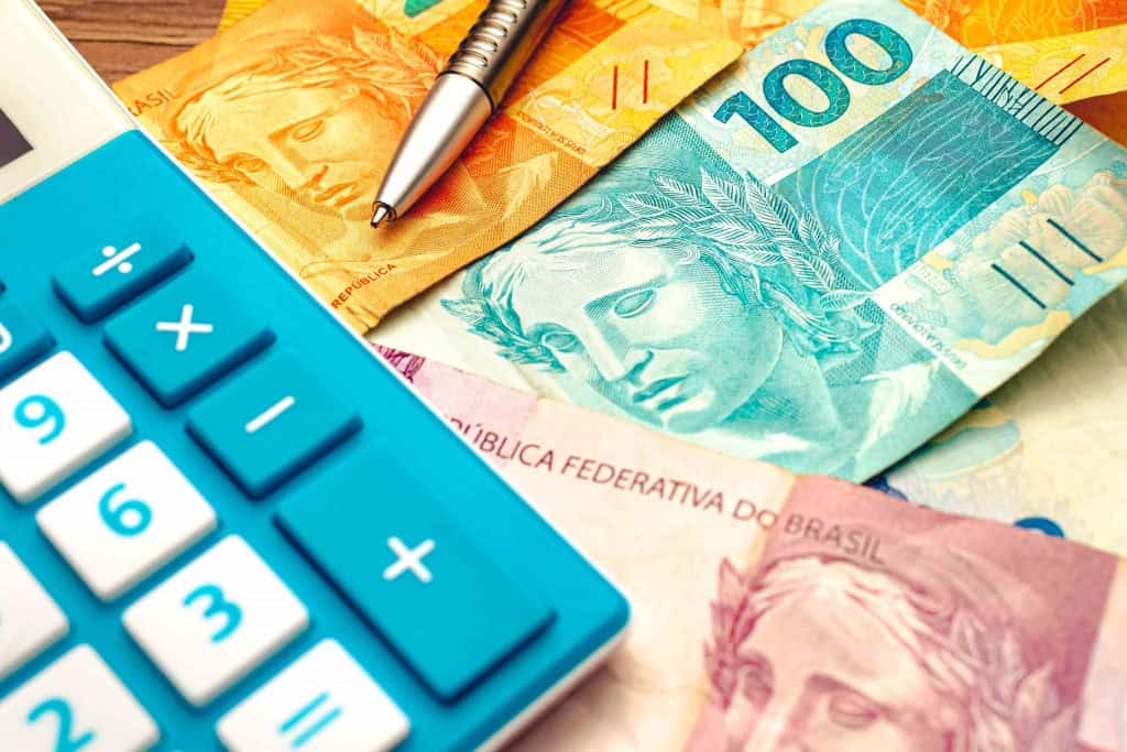Notas de reais e calculadora, simbolizando cálculo de investimento