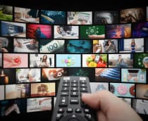 Várias janelas de streaming abertas; à frente, uma mão segurando um controle