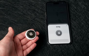 Pessoa com AirTag na mão ao lado de iPhone