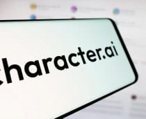 Celular com logomarca da Character.AI na tela; aparelho está na frente de monitor exibindo tela da plataforma