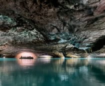 Barco com pessoas em lago subterrâneo em caverna