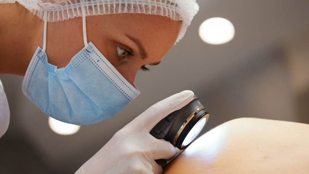 Médica fazendo exame de câncer de pele