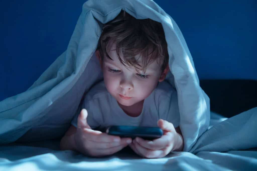 Criança deitada usando um smartphone