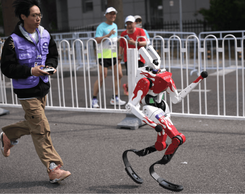 Integrante de uma equipe correndo atr&aacute;s de um rob&ocirc; operado por controle remoto. 