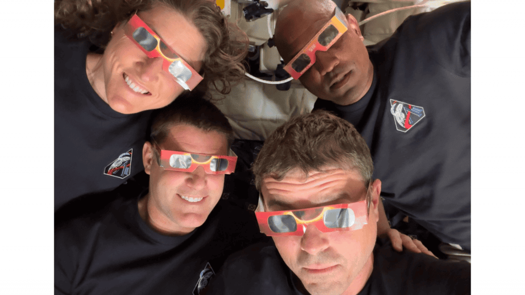 Astronautas (Christina Koch, Jeremy Hansen, Victor Glover e Reid Wiseman) da missão artemis 2 flutuanto na nave e com óculos especiais para assistir a um eclipse