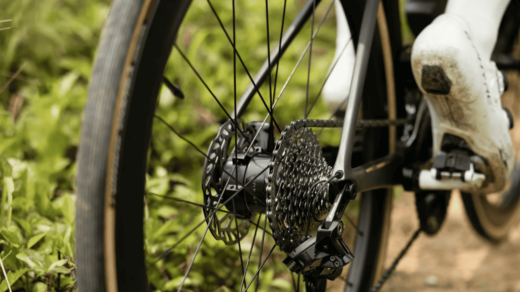 Bicycle wheel in focus while someone pedals. 