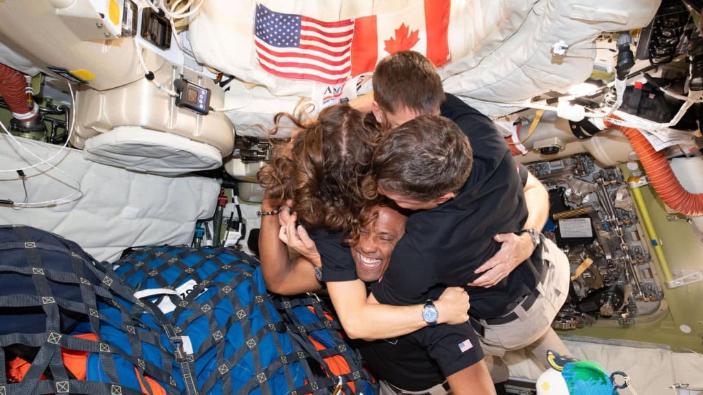 Abraço grupal entre membros da tripulação da Artemis 2 na nave Orion