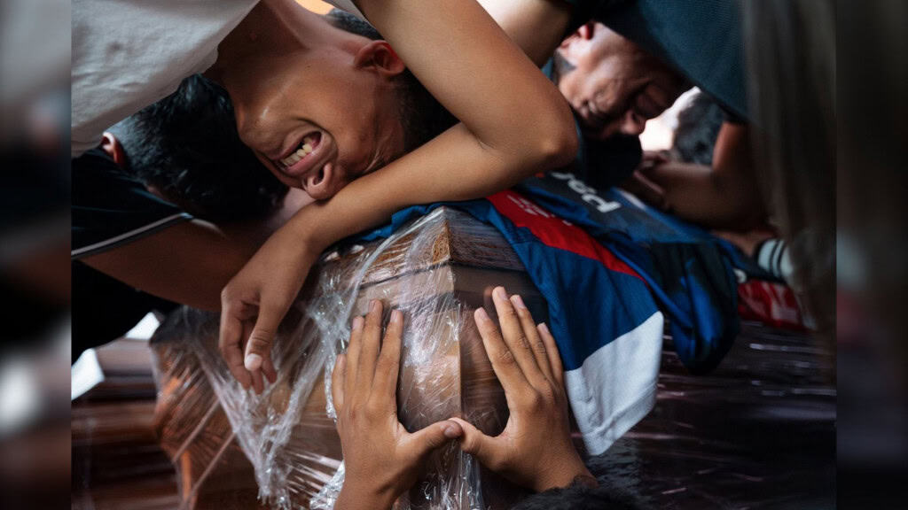Pessoas chorando em volta de caixão durante funeral