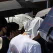 imagem mostra pessoas embaixo de guarda chuvas para se proteger do calor