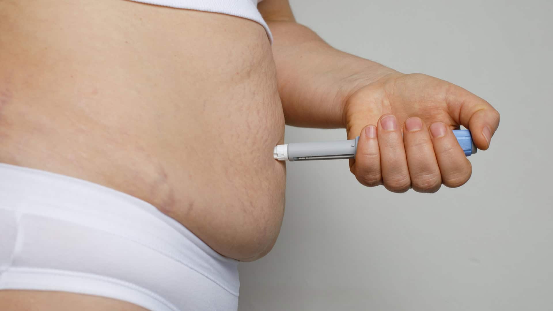 Pessoa aplicando uma caneta emagrecedora em sua barriga