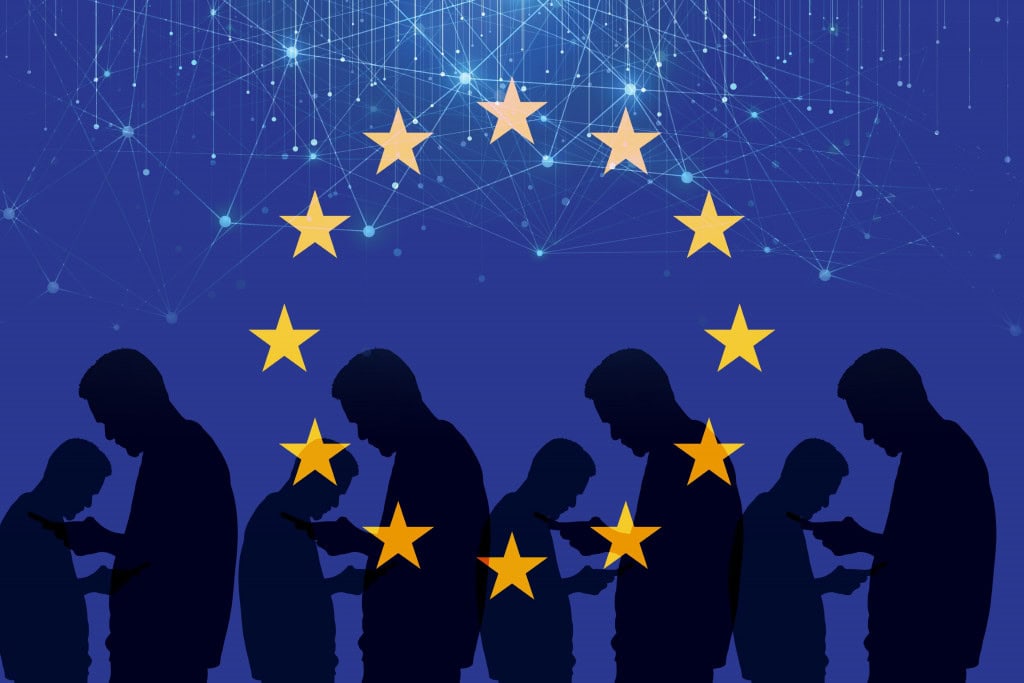 Pessoas visualizam o celular em fundo com a bandeira da União Europeia