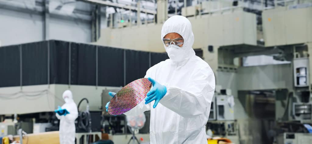 Operador em fábrica de semicondutores segura wafer de silício em ambiente controlado
