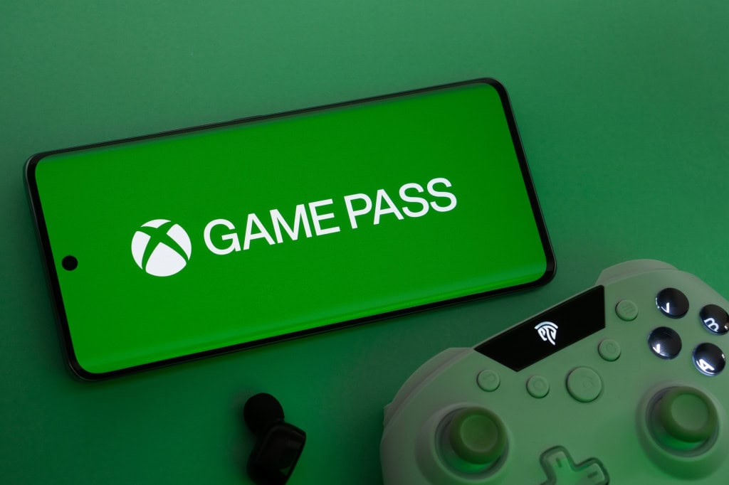 Logo do Xbox Game Pass em um smartphone na horizontal; abaixo, um joystick