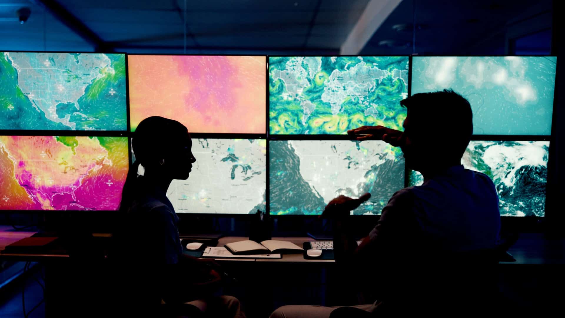 Sombra de pessoas conversando diante de monitores